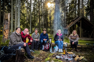 mnänniskor sitter vid en lägereld i skogen