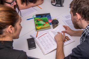 kursdeltagare i skolarbete på bordet ligger läroböcker och pennor.