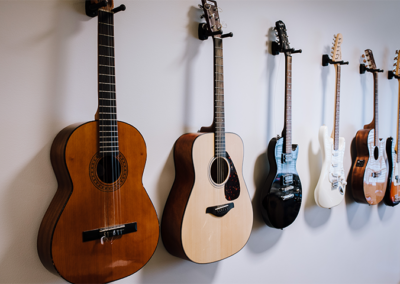 Flera olika gitarrer hänger på en vit vägg.
