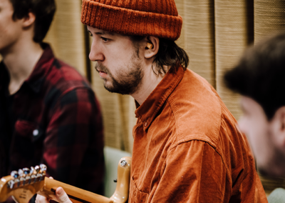 En gitarrspelande kille med mössa från skolans Musiklinje.