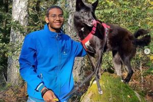 Glad husse med hunden på en sten i skogen