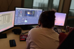 Person sitter vid dator med ryggen mot kameran och arbetar i ett adobe cc program