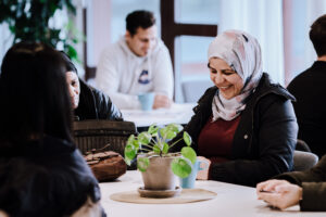 kvinna med hijab sitter vid bord och ler