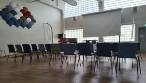 Bild på stolar uppställda i en sal framför en scen med en projektor.