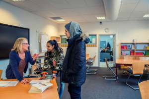 Lärare pratar med två elever i ett klassrum