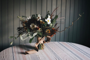 en bukett som står på ett bord med grenar och blommor som yvigt sticker utt